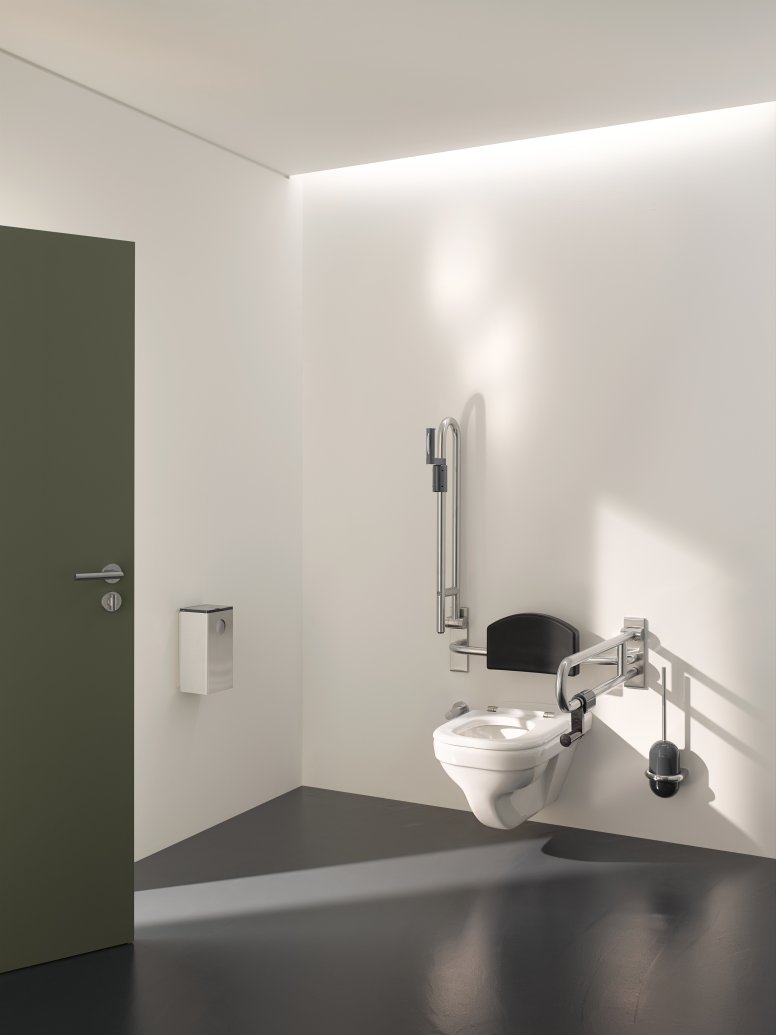 Barrier-free WC in public areas equipped with folding support handles, back support and toilet brush
